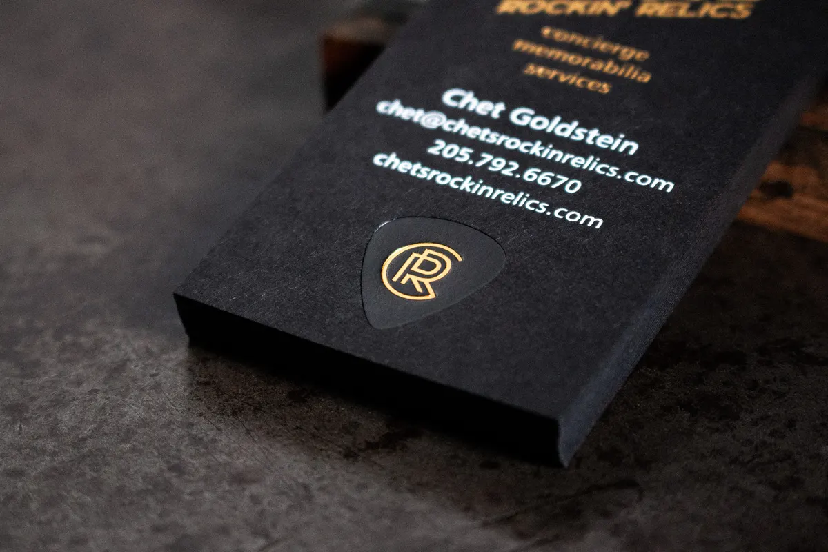 Spread of foil stamped business cards on dark surface showing both sides of the design