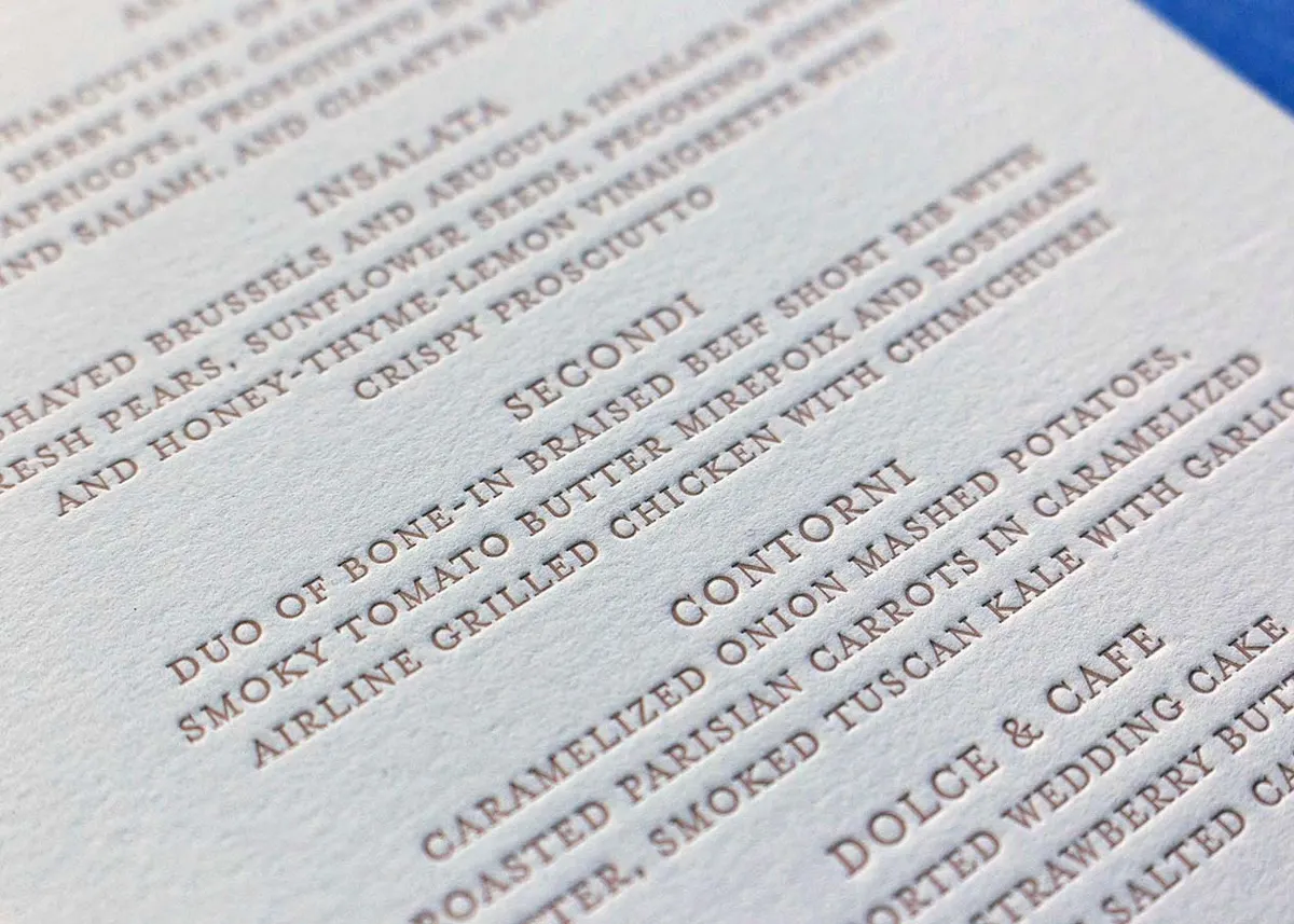 Detail of letterpress menu text printed in soft pink ink showing course listings