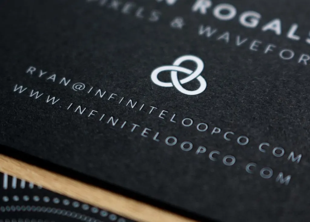 Stack of black business cards with white foil stamping showing the duplexed edge