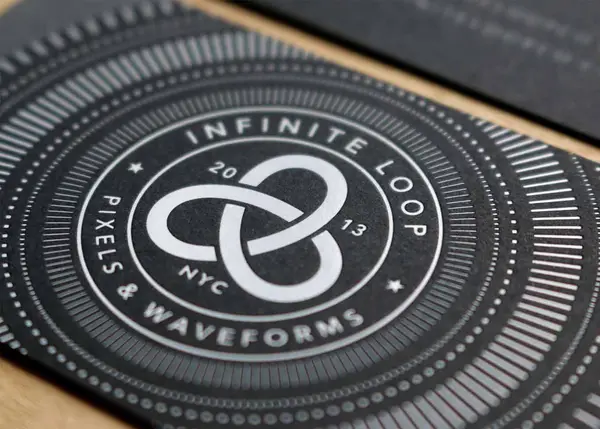 White foil stamped business cards on black paper with geometric pattern